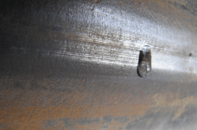 Water leaking from a seamed pipe.