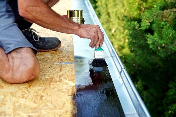 Figure 1. Worker applying a polymer modified bitumen waterproof coating to a rooftop.